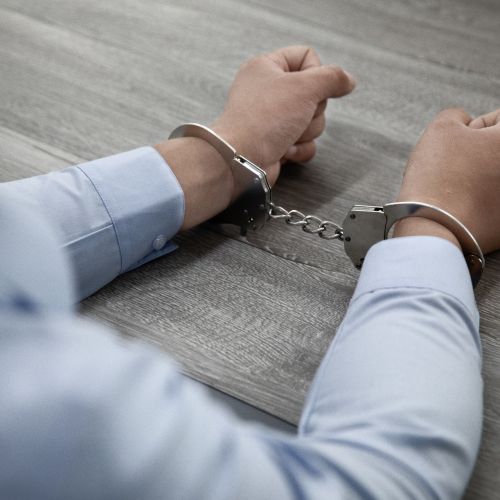 Selective focus shot of male hands in handcuffs on a wooden table